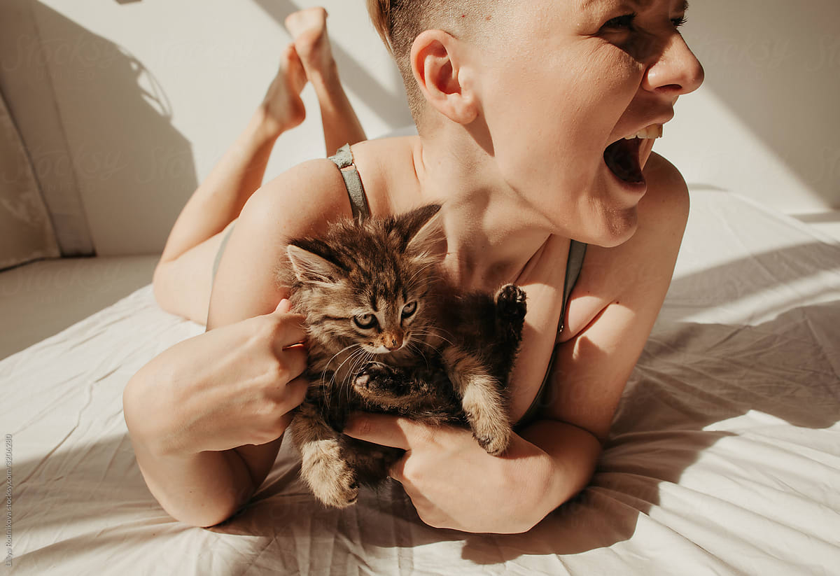 Excited woman with kitten on bed
