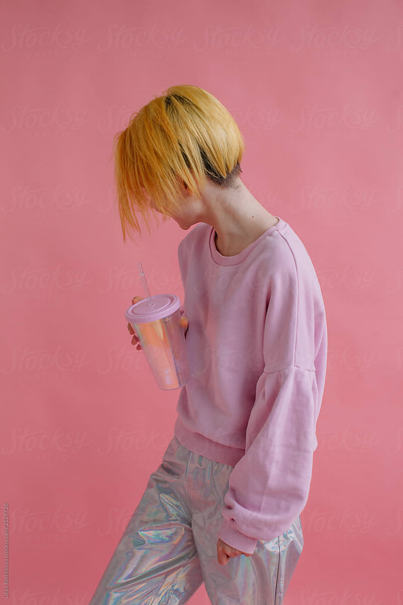 Unrecognizable girl with yellow hair posing in pink studio