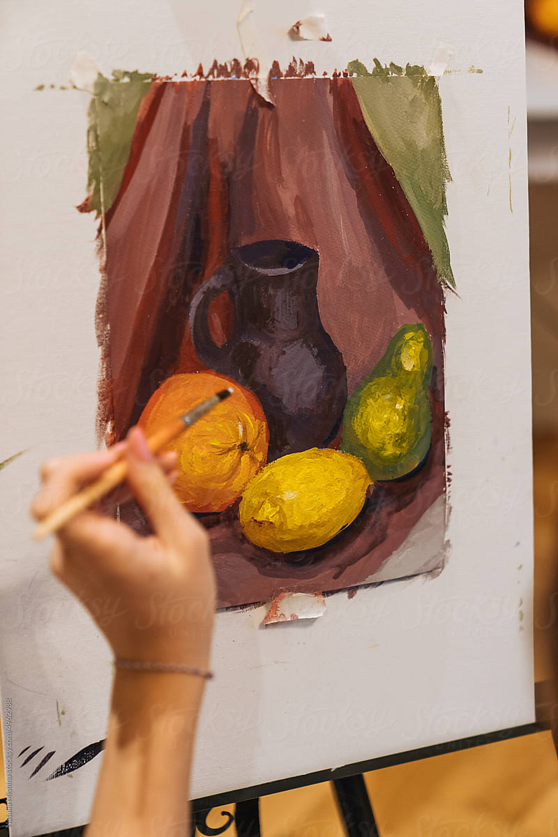 A woman's hand holds a brush, draws a still life.