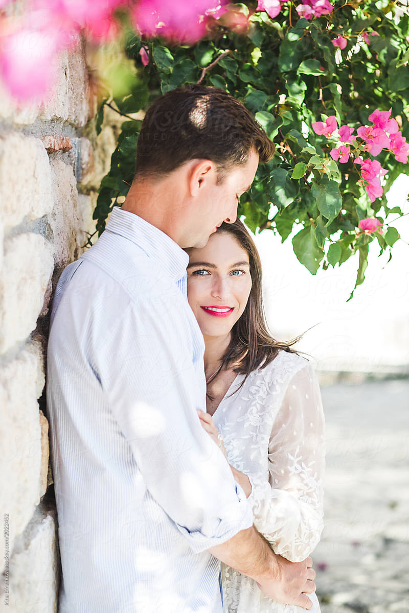Couple in love standing under beautiful blooming fuchsia flower tree