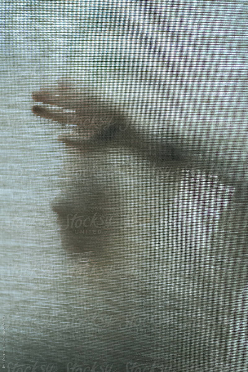 outlines of a woman\'s face and hands through a translucent fabric