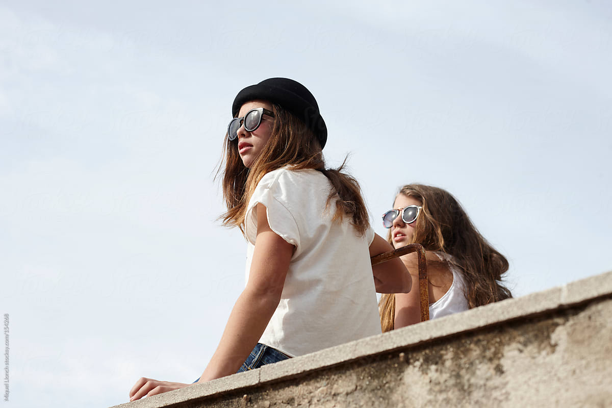 Fashion Young Girls Sitting On Rooftop With Sunglasses Looking Away