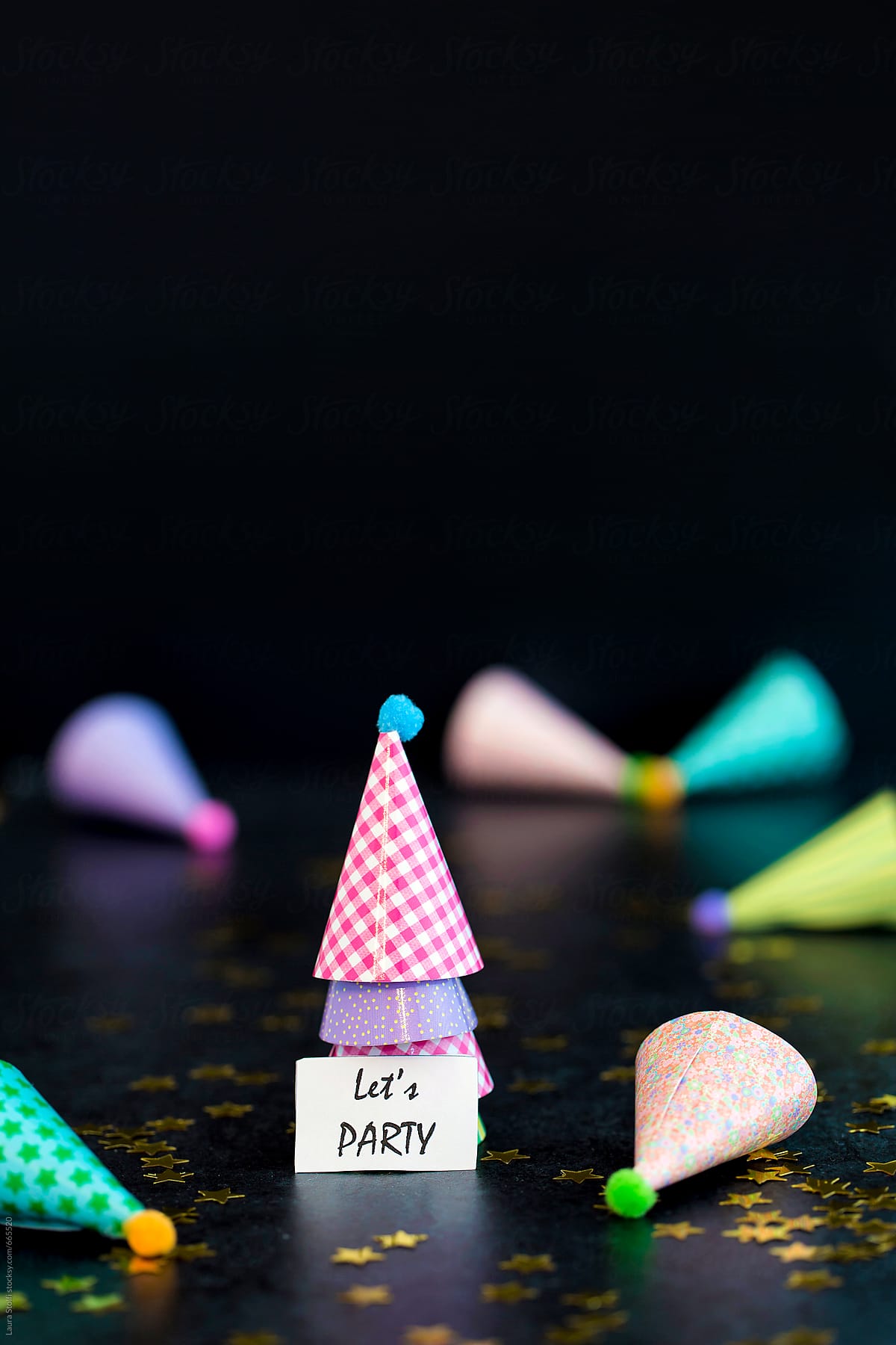 Let\'s party message in front of multi colored party hats
