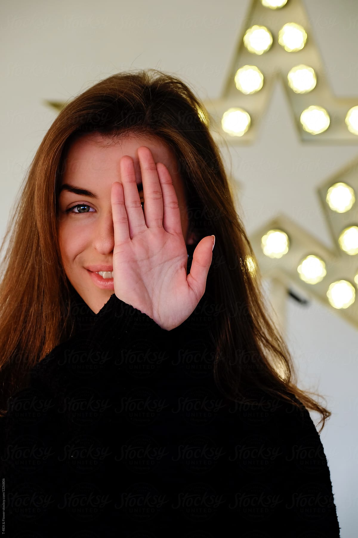 Smiling woman covering eye with hand