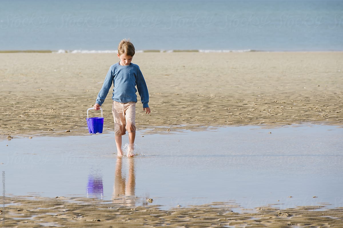 Child carrying water in bucket at the seaside