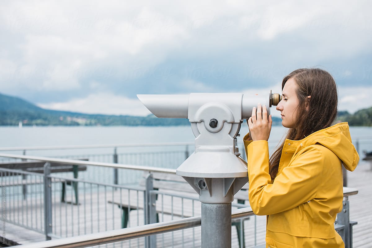 Woman in yellow coat looking through a telescope