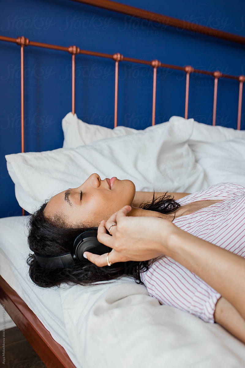Young woman relaxing on the bed with headphones and enjoy the moment