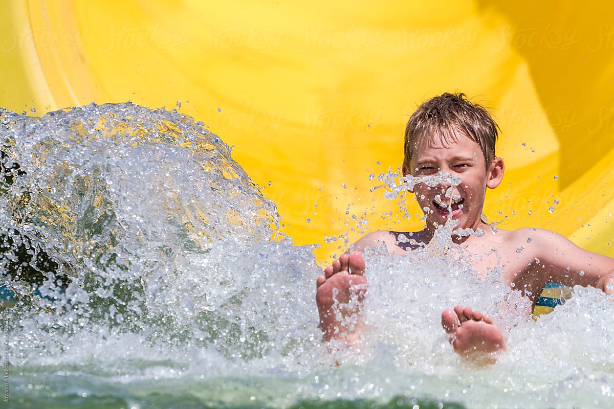 Boy making water splash after aqua park tube sliding