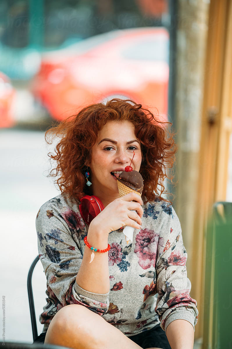 Cheerful woman eating delicious ice cream on street