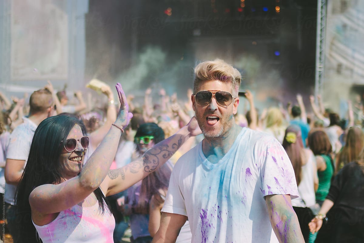 young colorfully painted couple dancing at an outdoor music festival