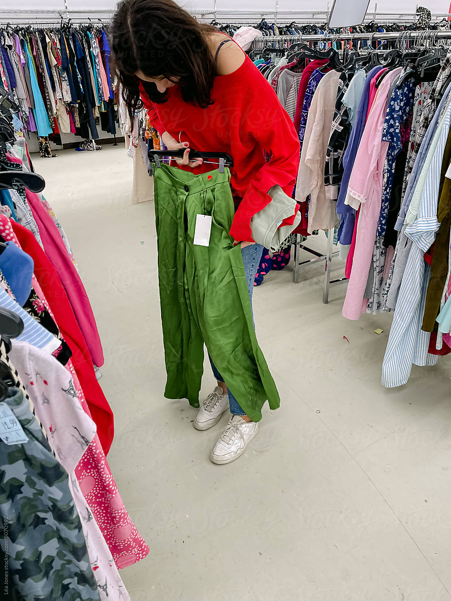 young woman buying pants at thrift store