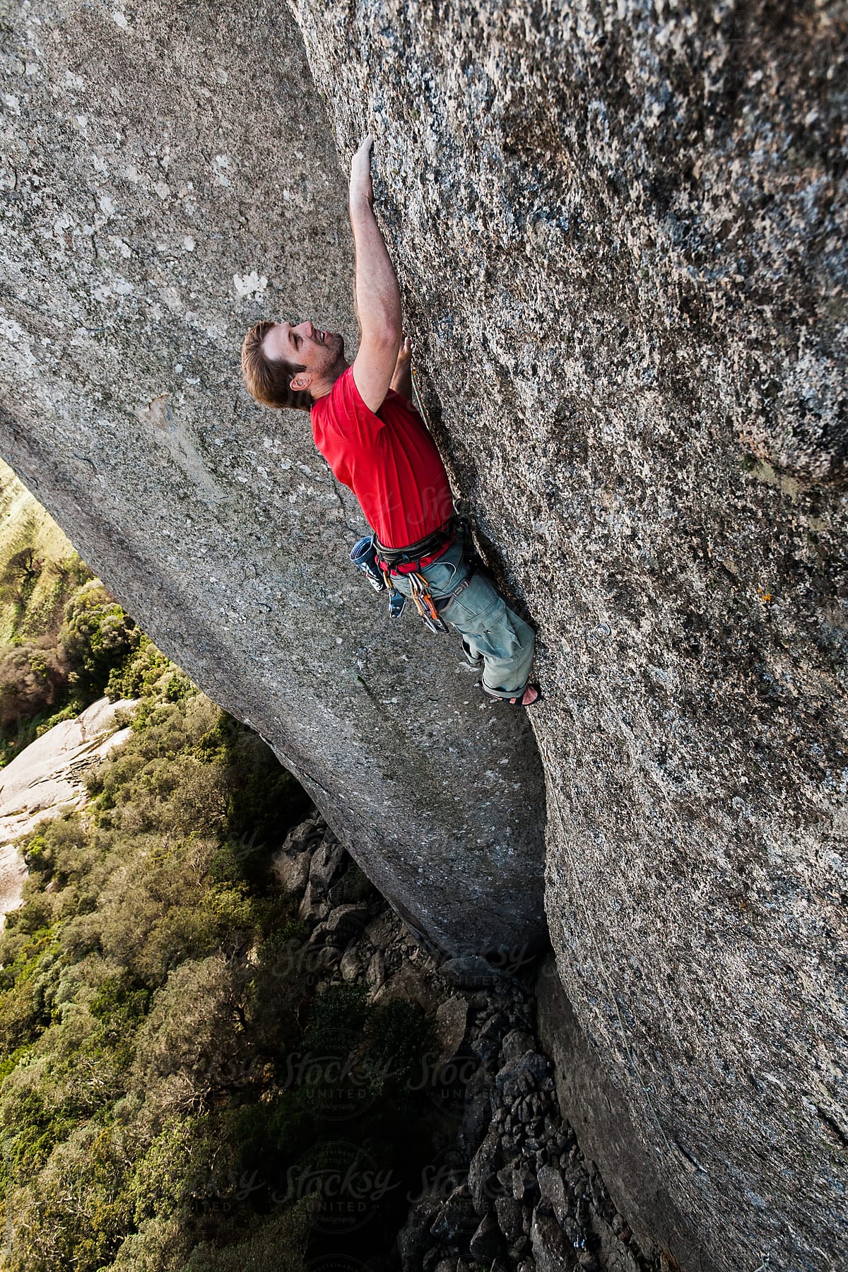 Male rock climber climbing a vertical cliff face in a mountain