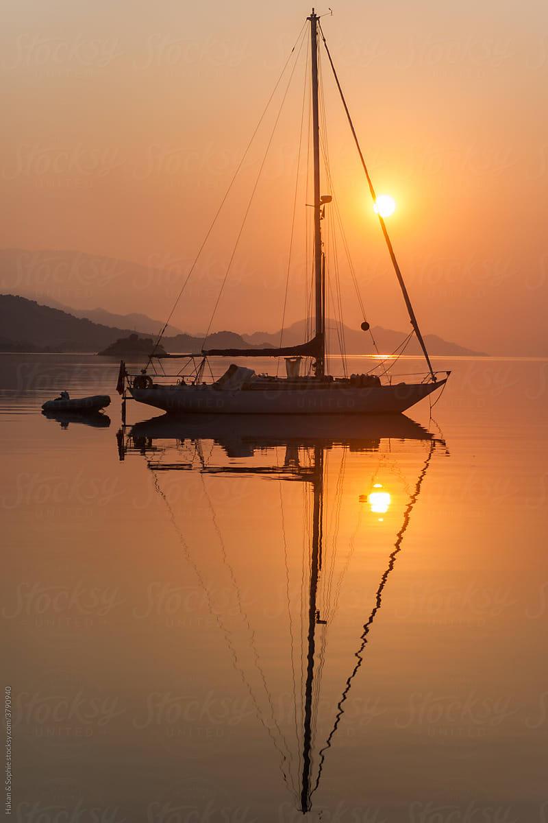 elegant sailboat and its reflection in orange light