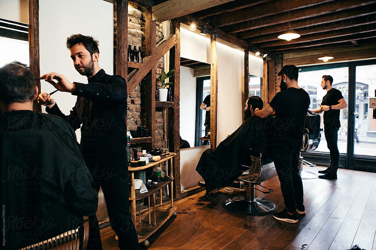 A busy barbershop with barbers and customers