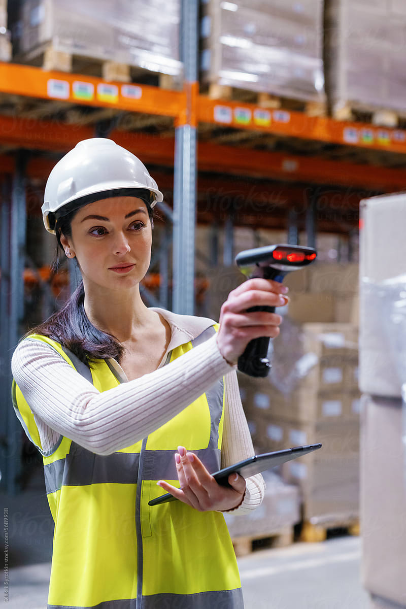 Girl using scanner tablet in warehouse aisle