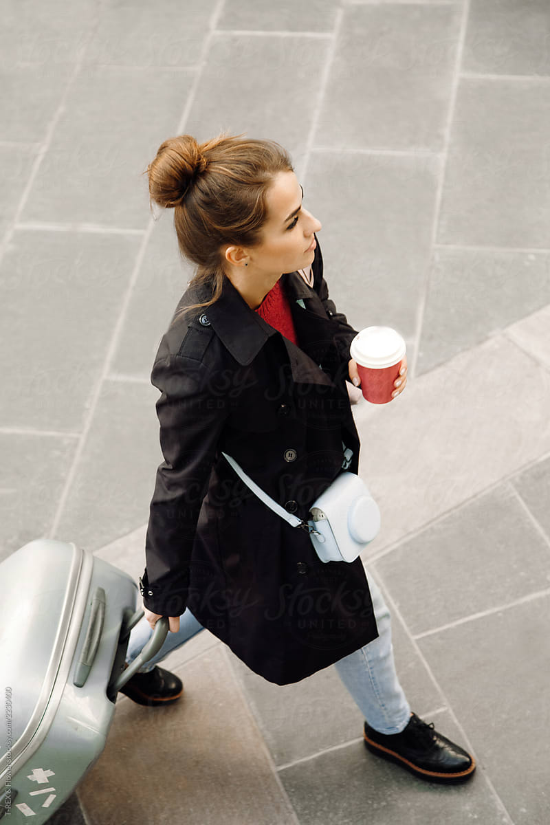 Young attractive woman with luggage and coffee
