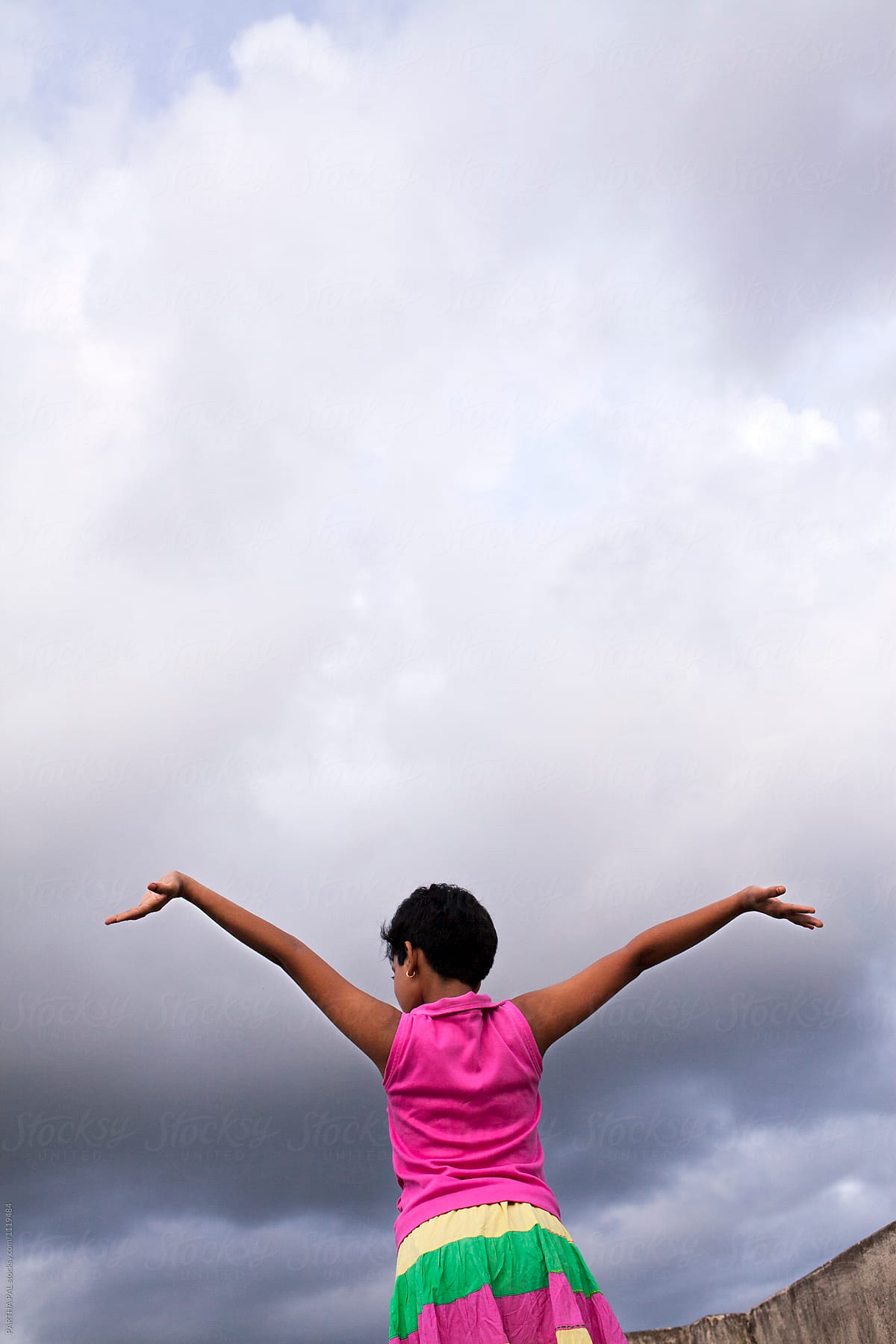 Teenage girl stretching arms with monsoon sky at backdrop