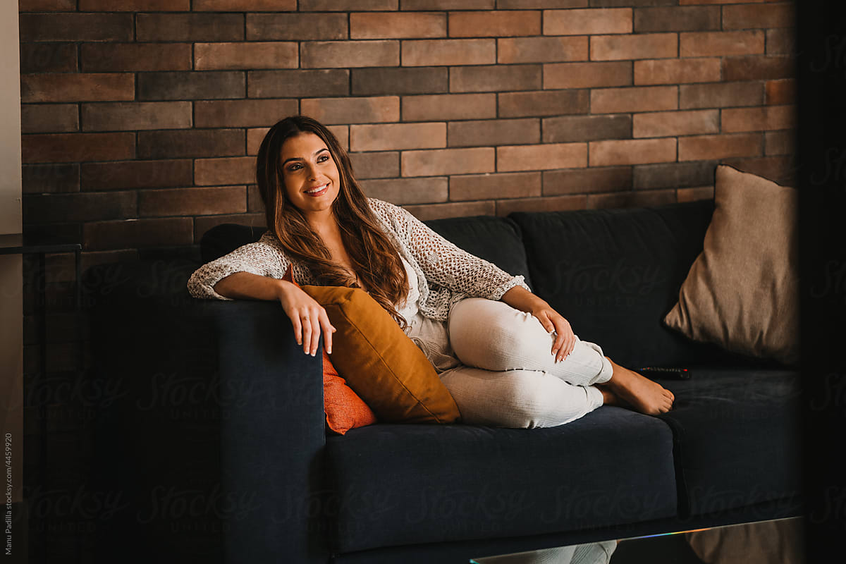 Smiling woman relaxing on couch and watching TV show