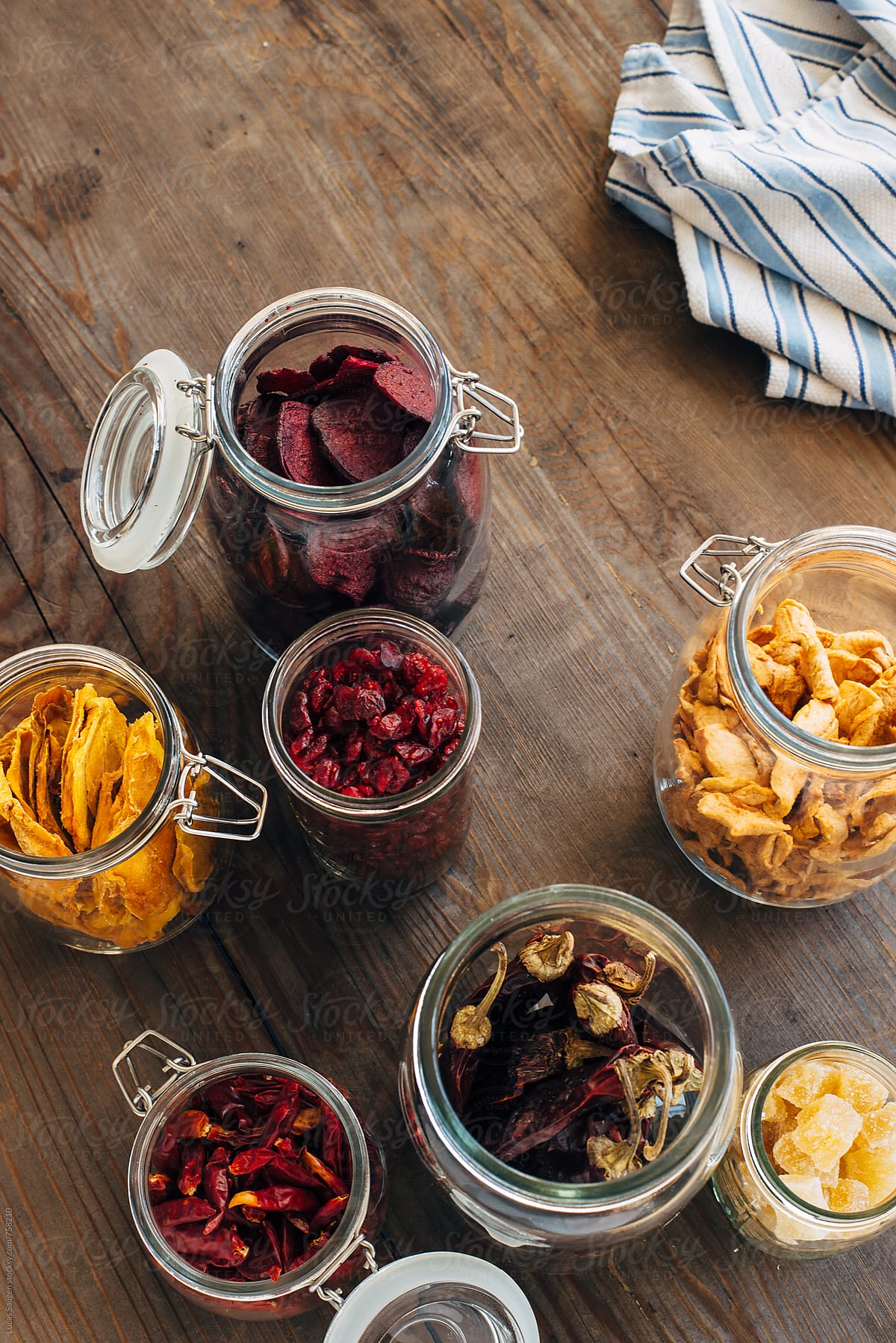 Overhead shot of open glass jars of dehydrated fruits and peppers.