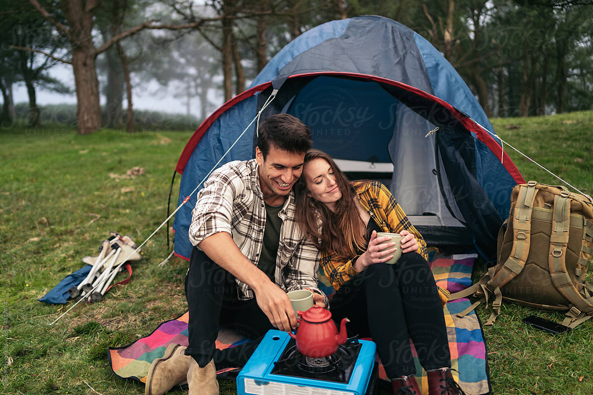 Affectionate couple camping in the forest and using camping gas