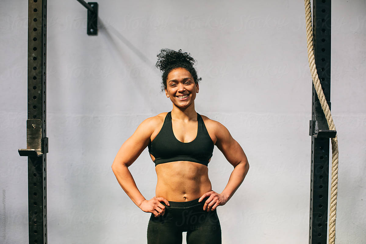 Positive Hispanic sportswoman during break in gym