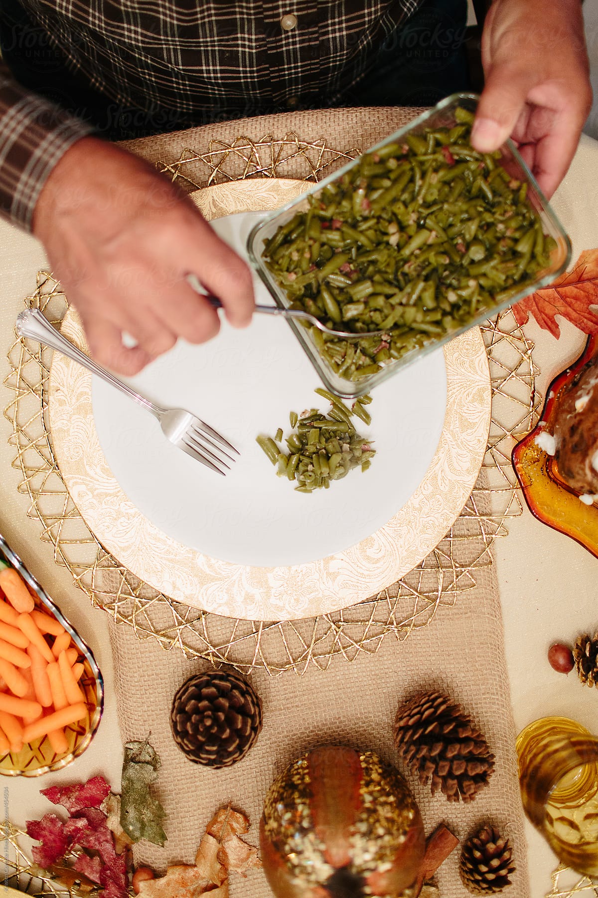 A man putting green beans on his plate at the dinner table