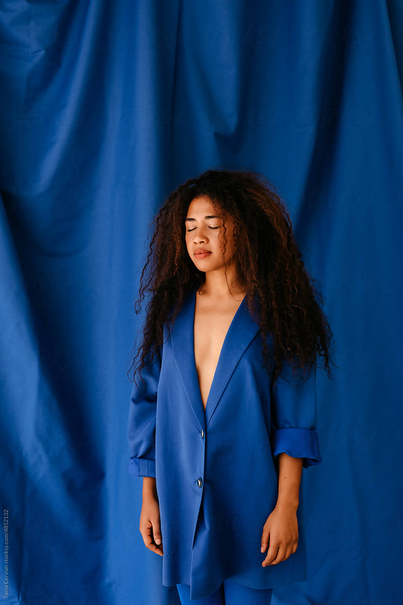 Stylish woman with closed eyes on blue background