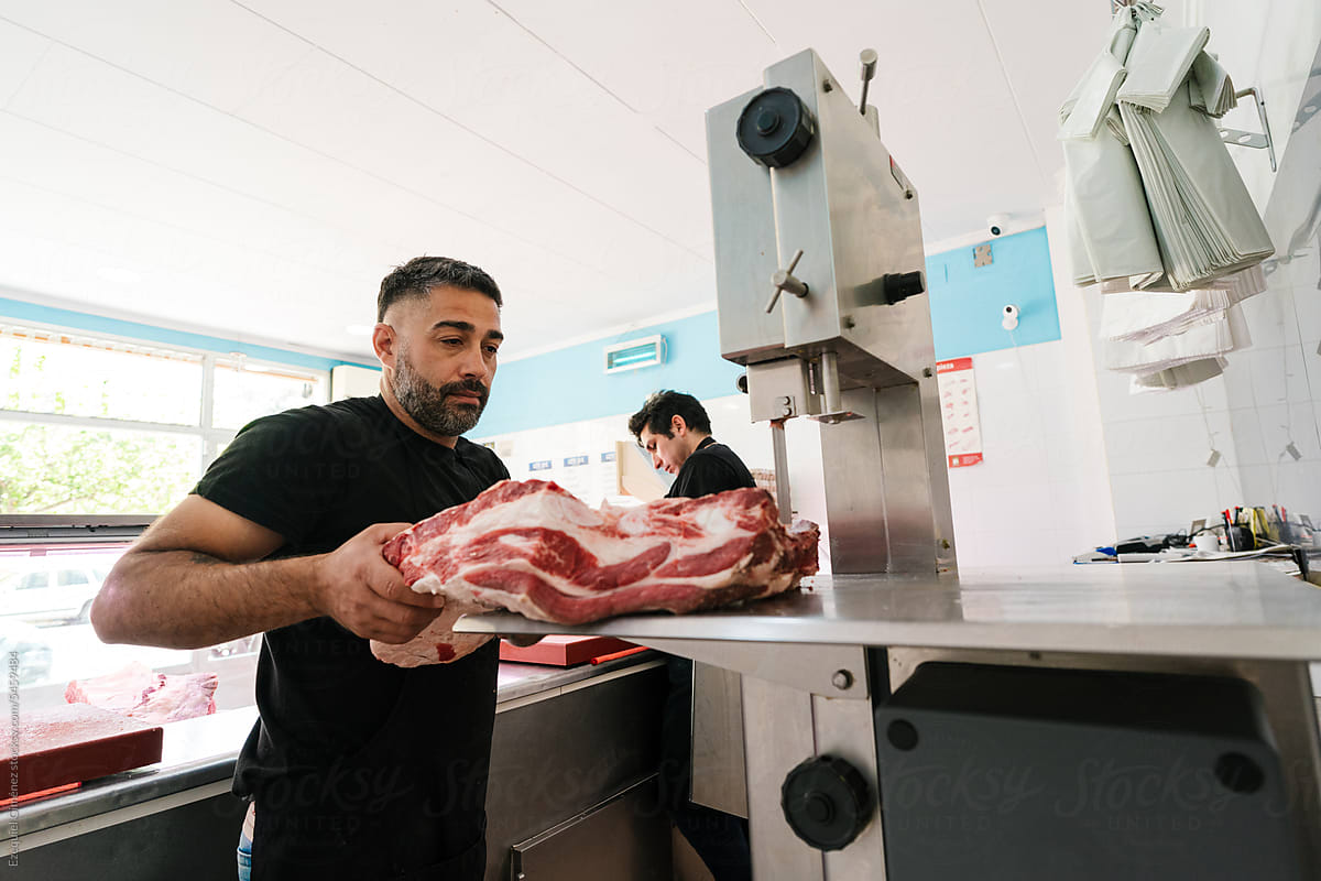 Male worker cutting meat in shop