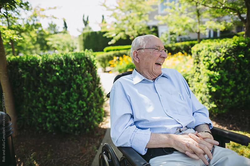 Happy, fun loving elderly couple outside in garden using wheelchair