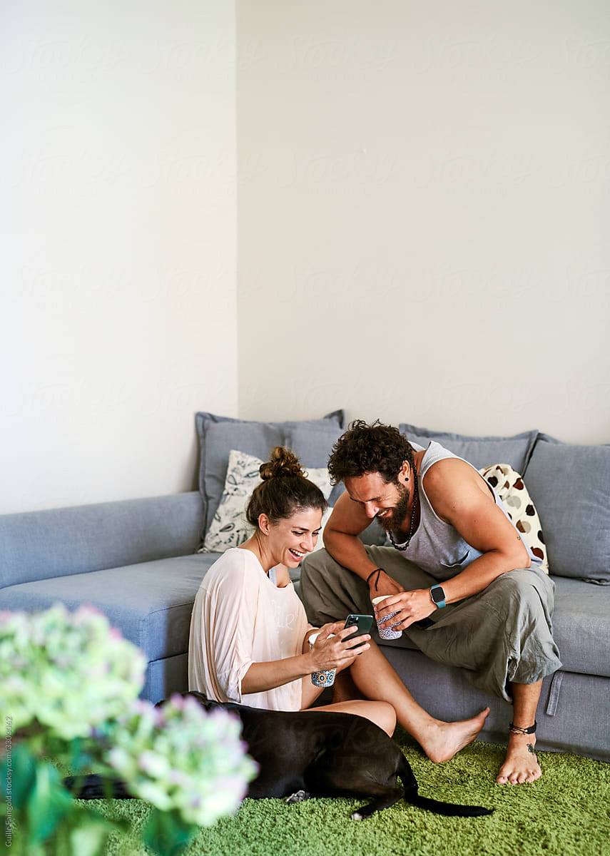 Happy couple using smartphone together at home