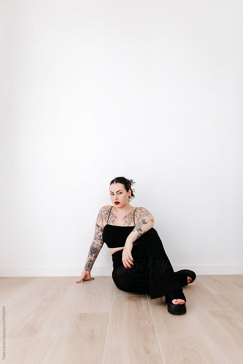 Serious tattooed woman sitting in studio