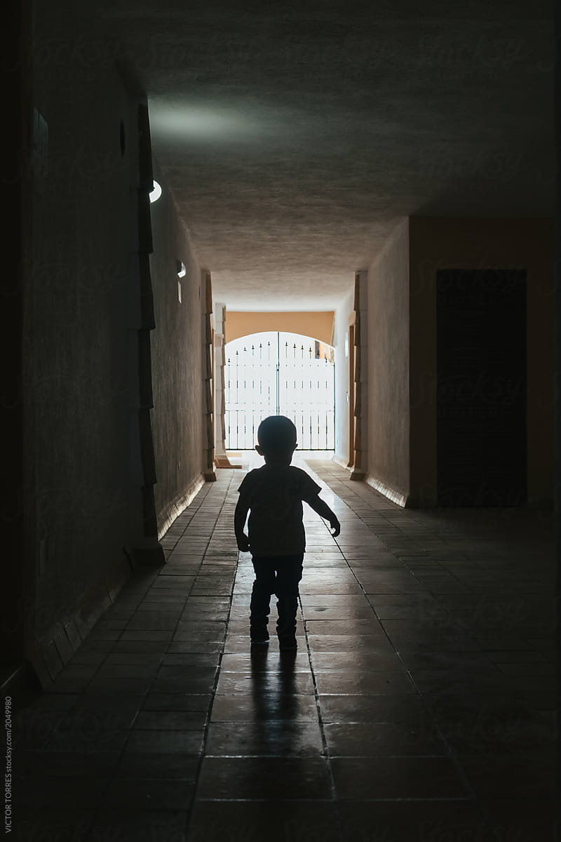 Little kid walking through a dark corridor