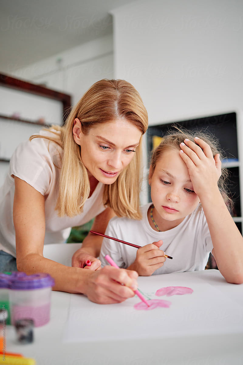Mother helping daughter painting picture for home task