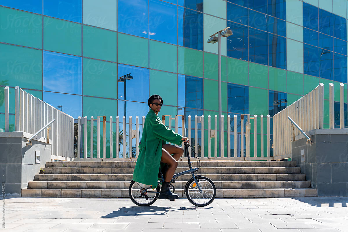 Green stylish man riding a bike at city