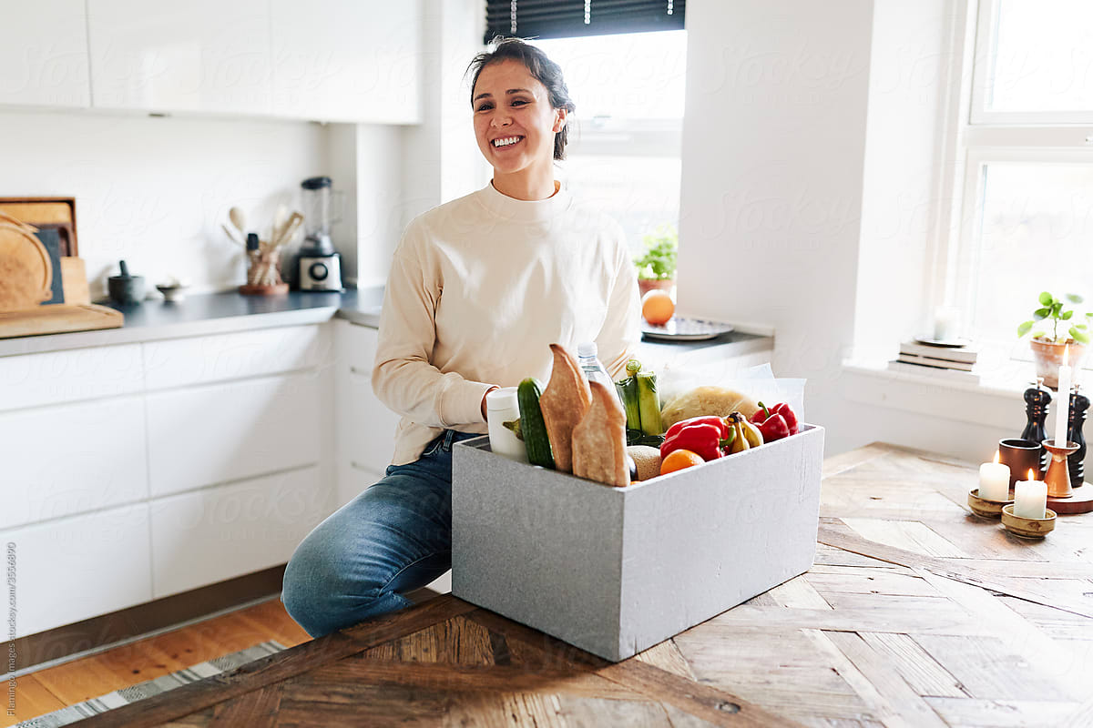 Smiling woman unpacking groceries at home