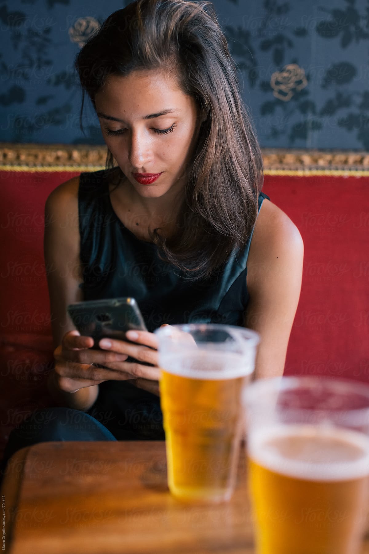 Woman uses social media while drinks a beer in a Pub