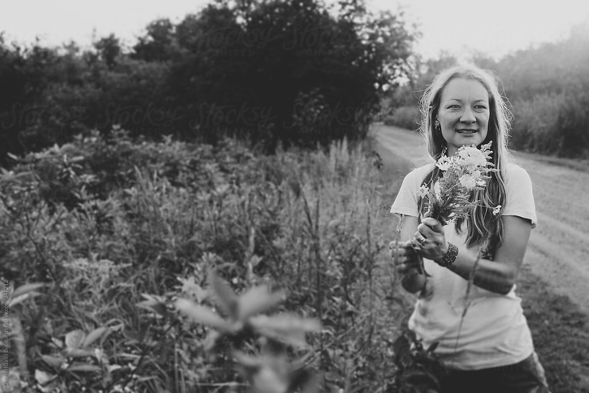 Black and White Portrait of a Woman Picking Wild Flowers  At Sunset By A Road Side