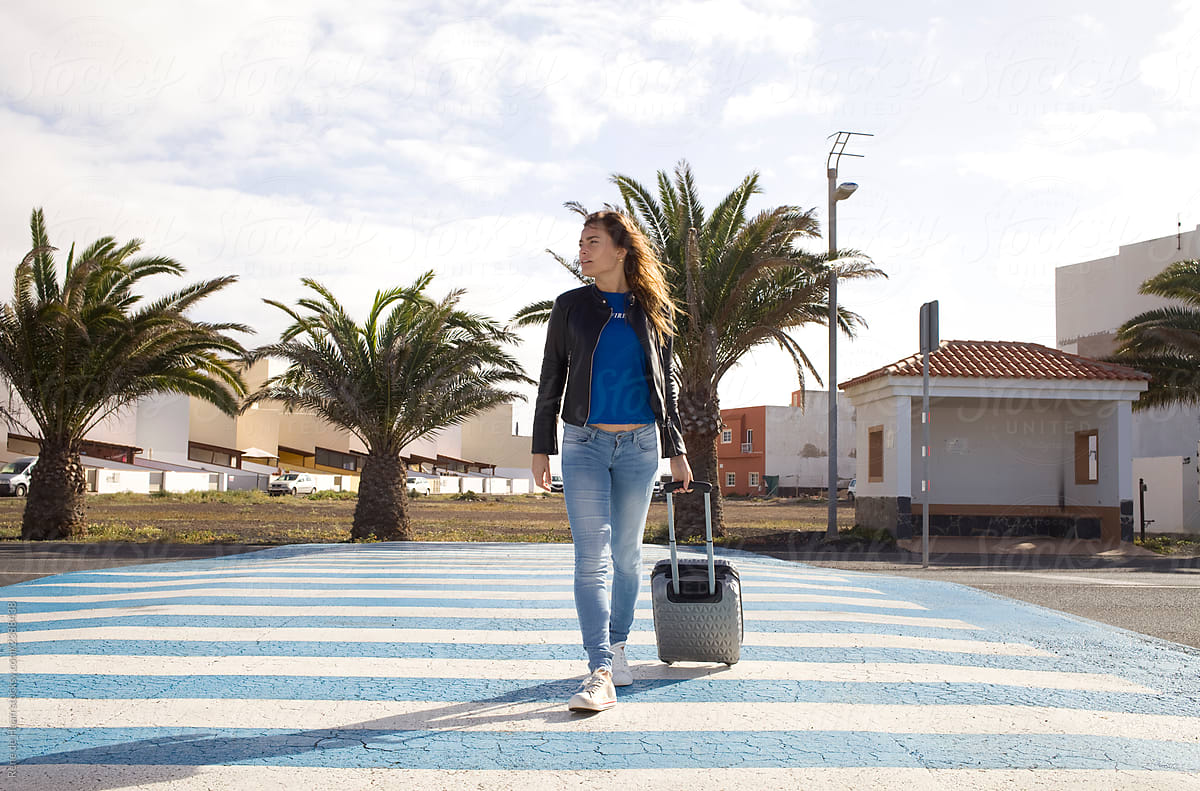 young woman on zebra crossing with suitcase