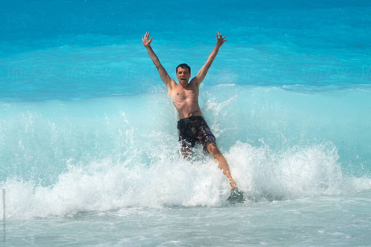 Man jumping into a turquoise sea wave splash