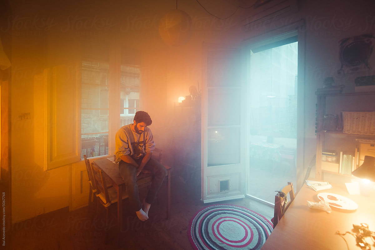 Sad man sitting on a table in surreal home