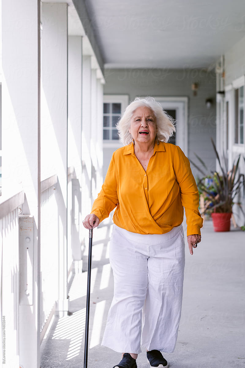 Mature woman wearing walking stick in nursing home complex