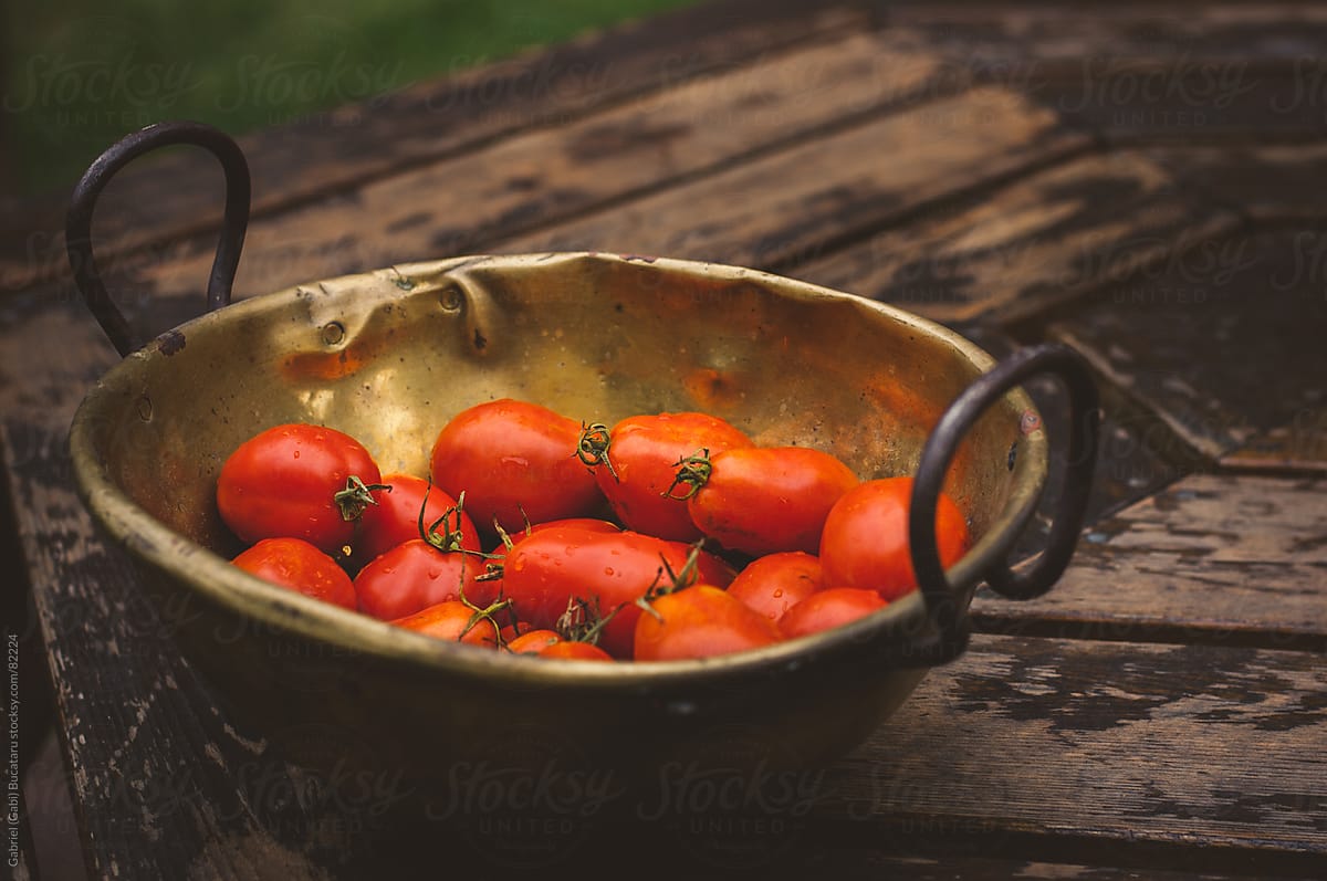 an antique brass bowl with fresh Roma tomatoes