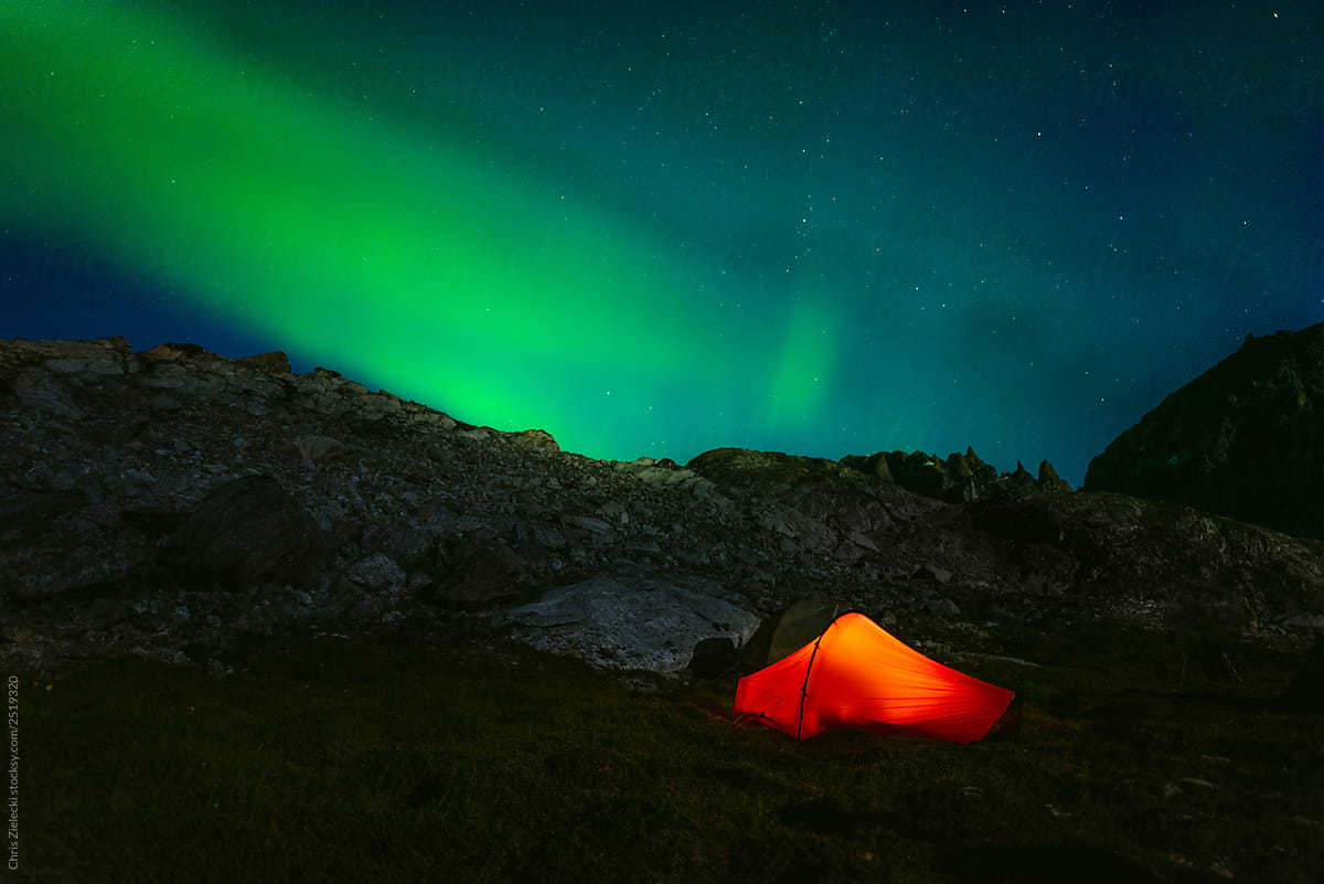 Red camping tent in night with north lights