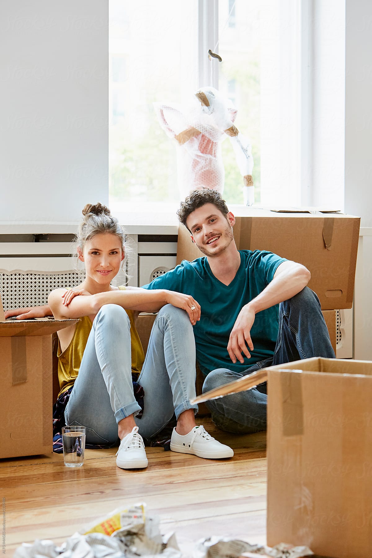 Happy Couple With Moving Boxes Sitting In New House