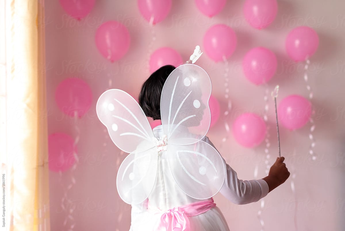 Little girl on her birthday dressed with butterfly wings holding magic stick