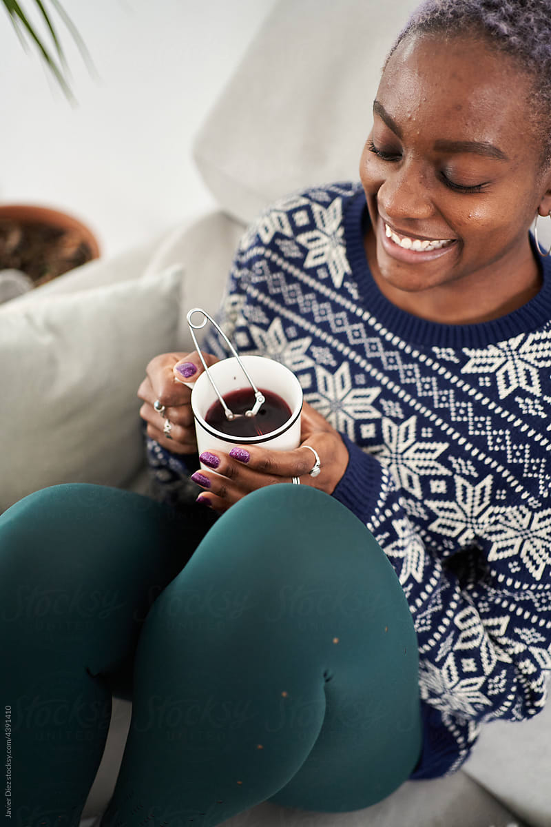 Smiling woman enjoying hot drink on couch