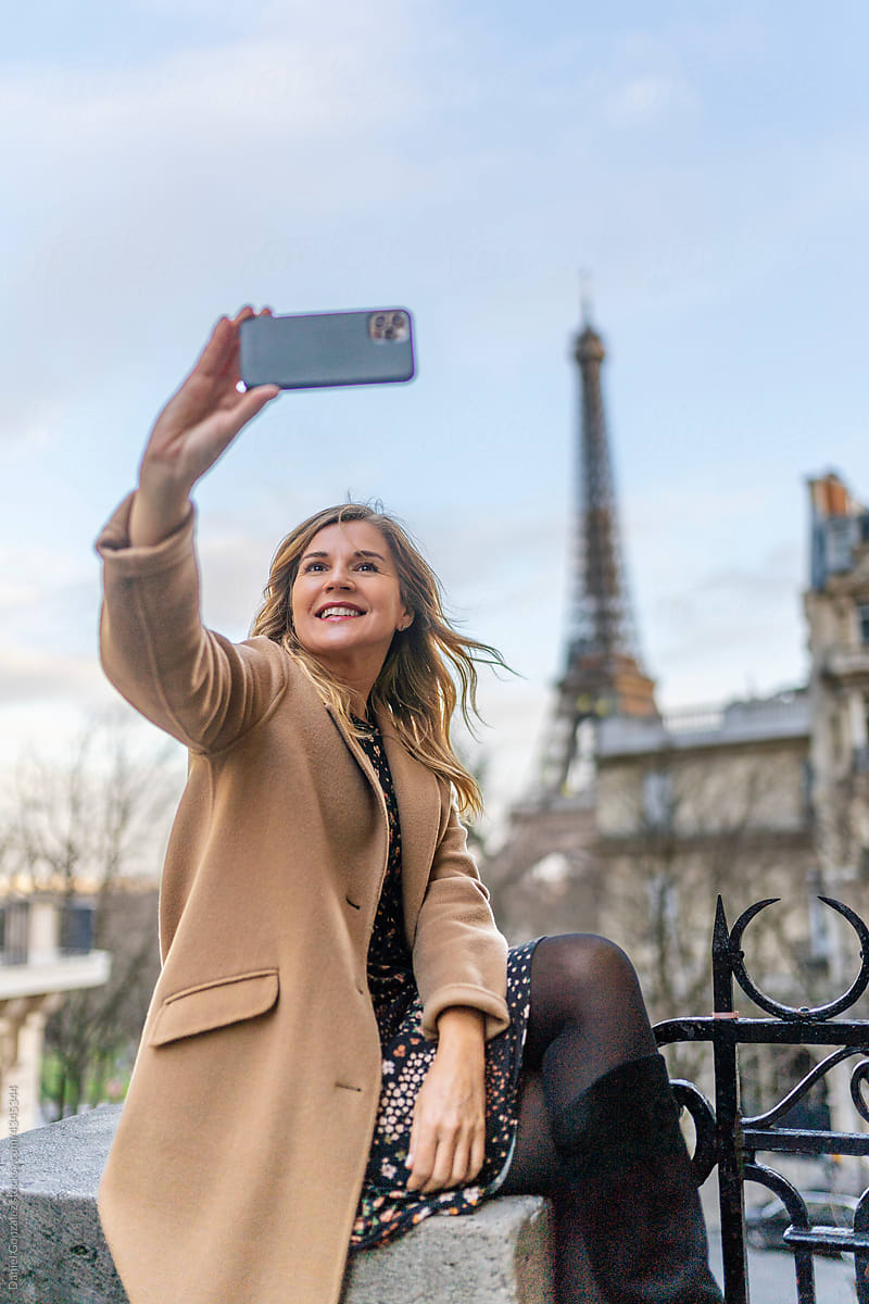Cheerful young woman taking selfie on smartphone