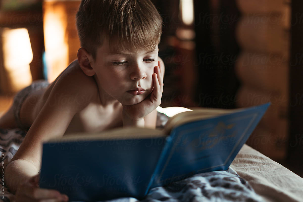 Young Boy Engrossed in Reading a Book Indoors