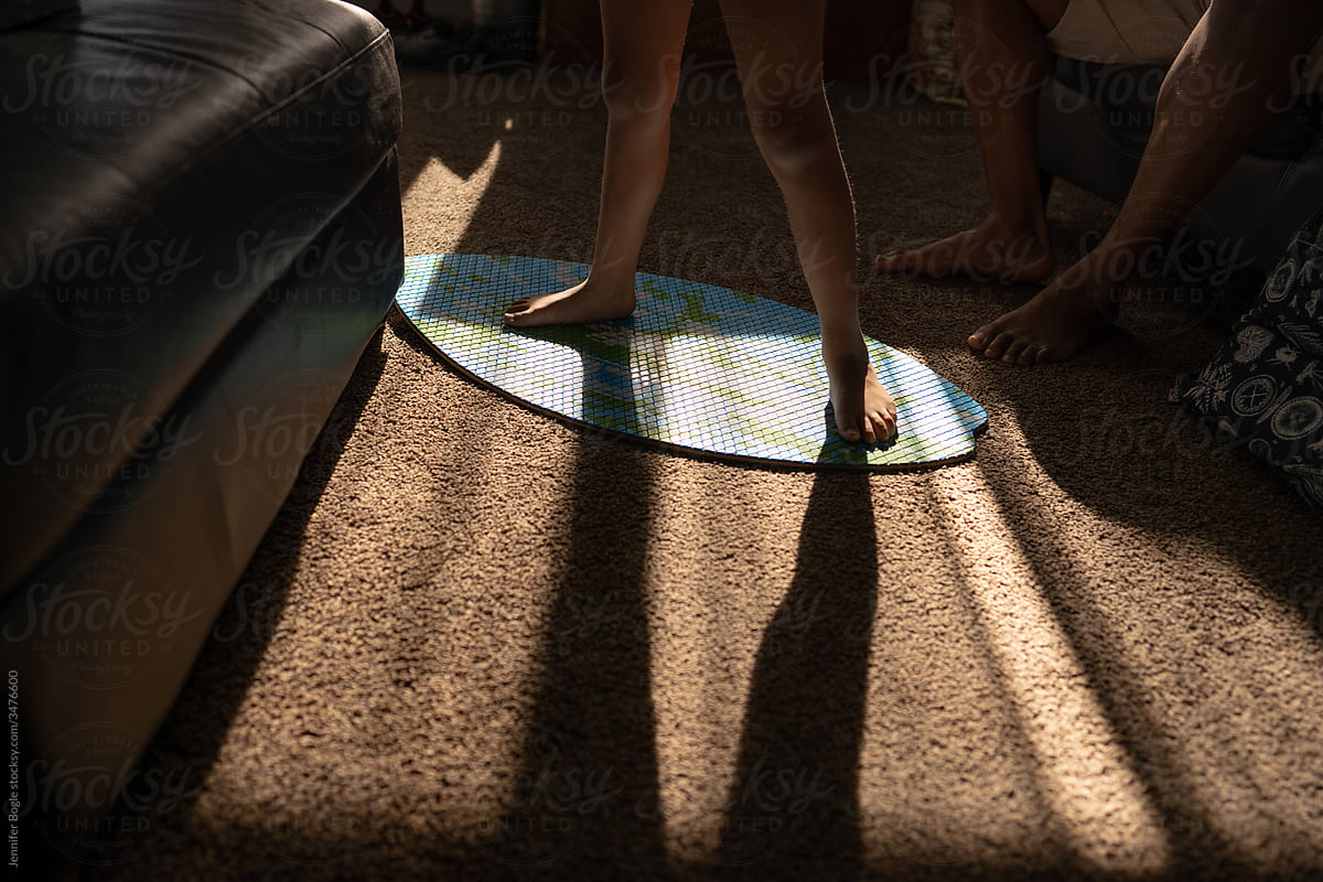 Barefoot child stands on skimboard indoors