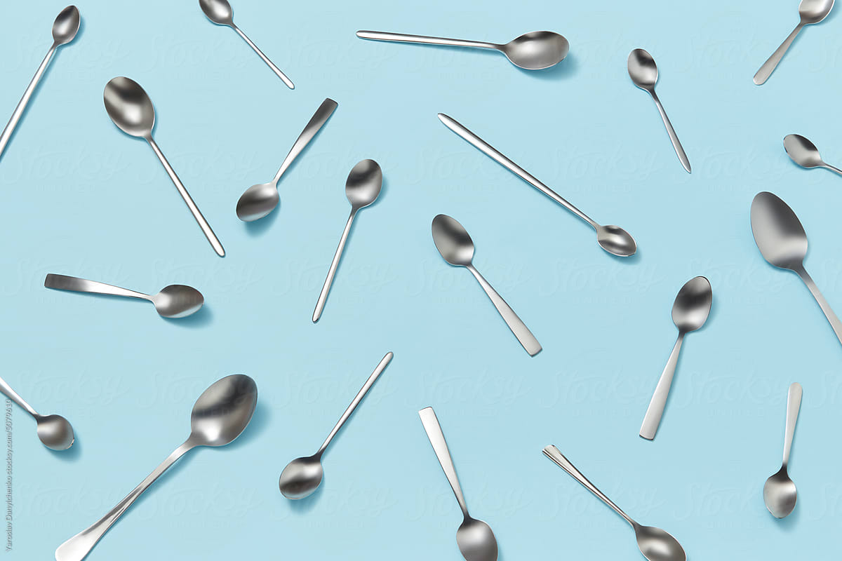Silver spoons scattered on blue background.